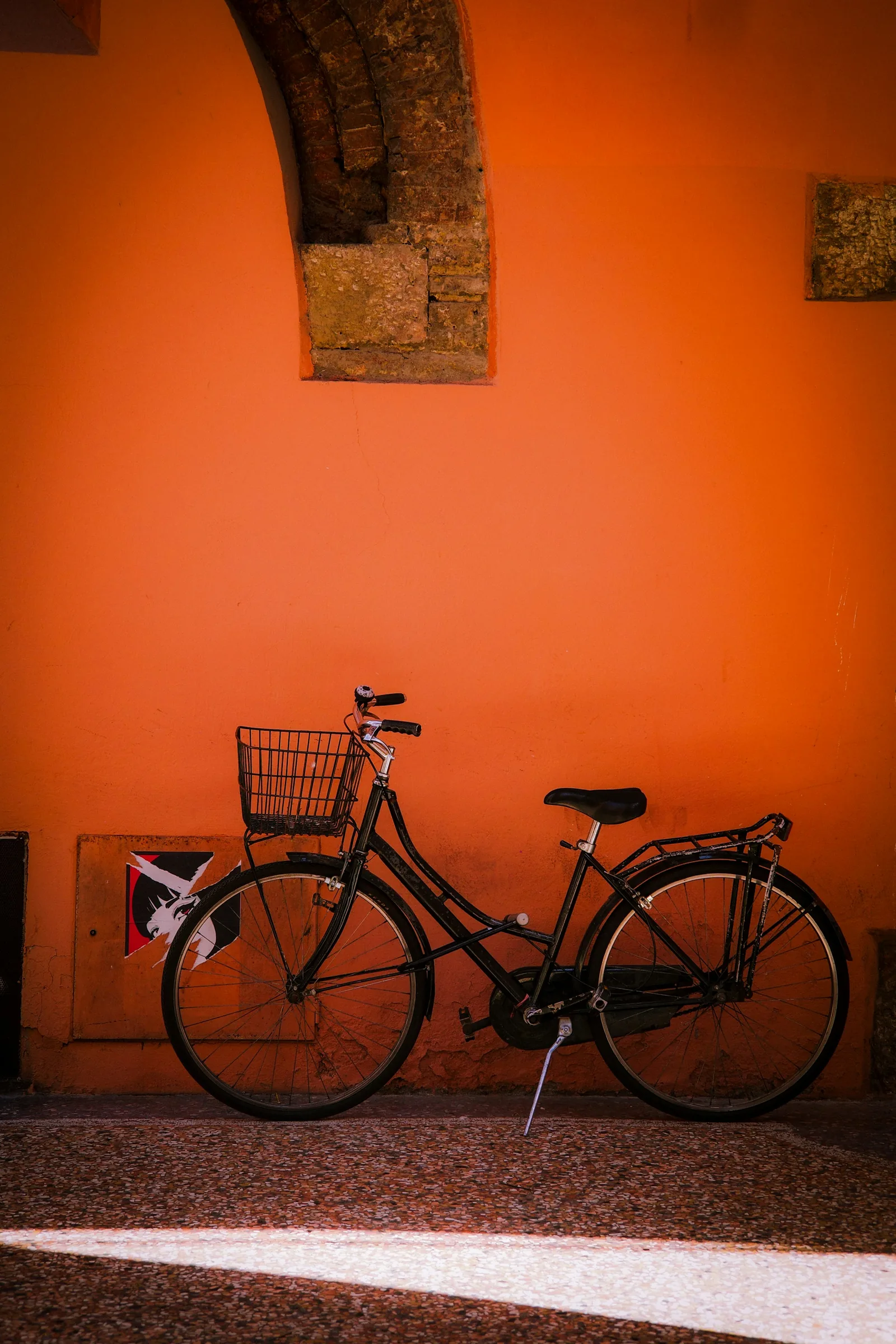 Black city bike with a basket against an orange wall