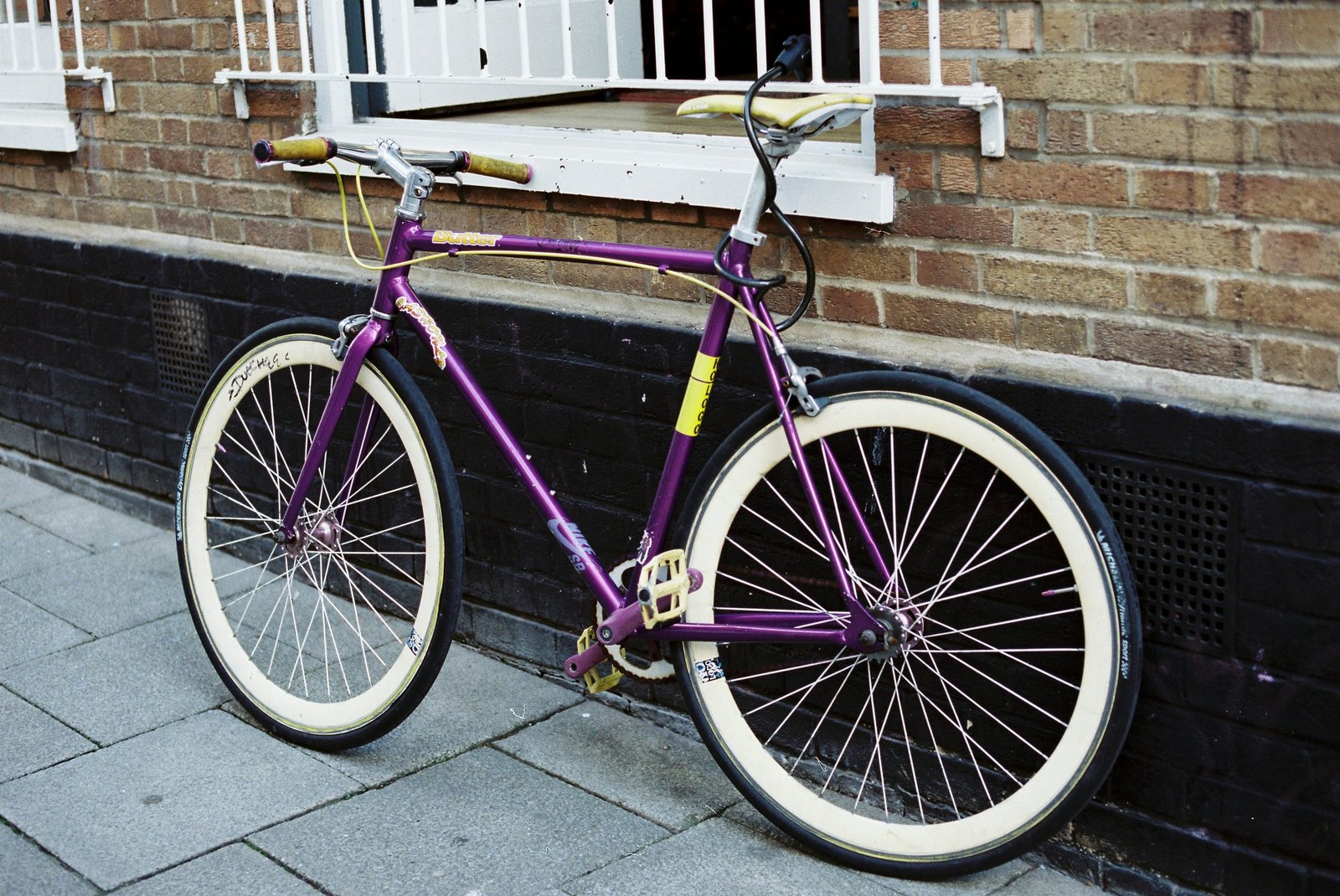 Purple vintage bicycle leaning on a brick wall